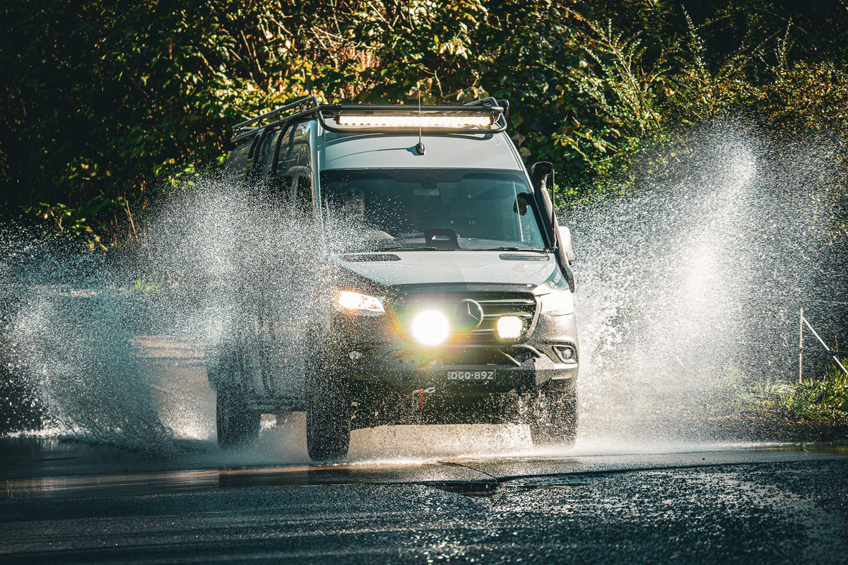 Mercedes Sprinter 4x4 campervan driving through floodwater on a bush road