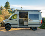 Burley Van Co Alta MWB Sprinter 4x4 campervan side profile, sliding door open, parked on the coast